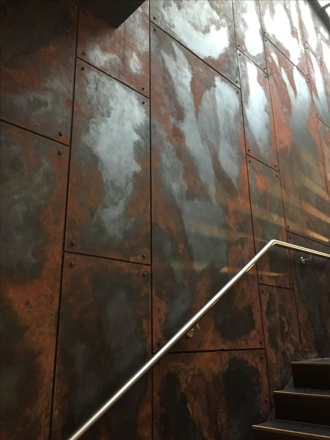 Patinated steel panel wall at a stair